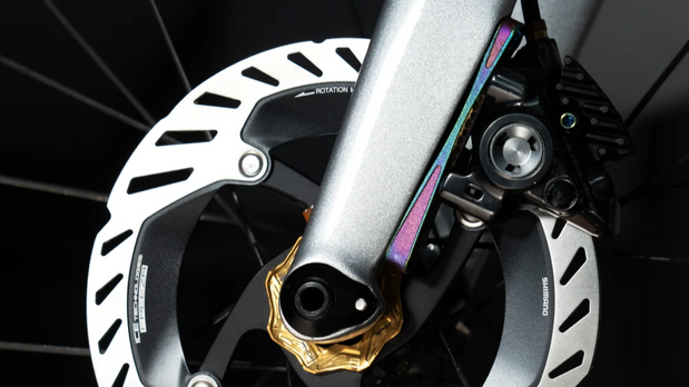 TiNE titanium brake hardware installed on silver bike fork near disc rotor