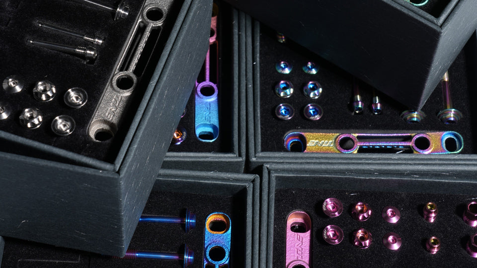 Assortment of colorful titanium bicycle bolts and accessories in dark cases