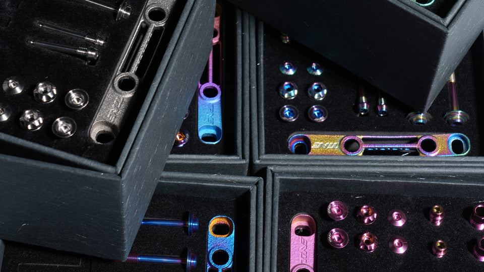 Assortment of colorful titanium bicycle bolts and accessories in dark cases