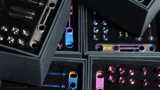 Assortment of colorful titanium bicycle bolts and accessories in dark cases