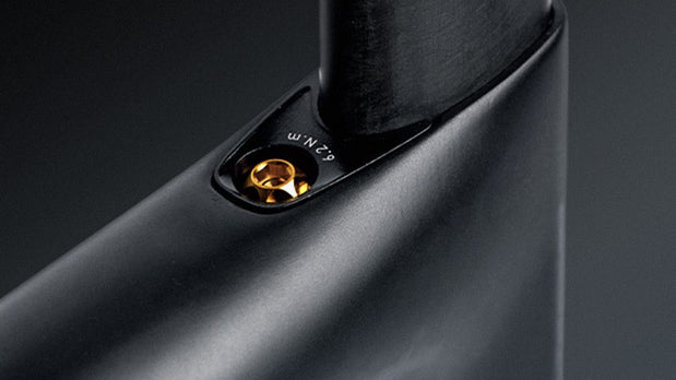 TiNE titanium seatpost clamp with gold hardware and torque marking on black frame