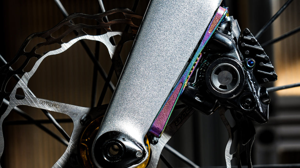 Titanium brake caliper bolt with iridescent finish on road disc brake assembly