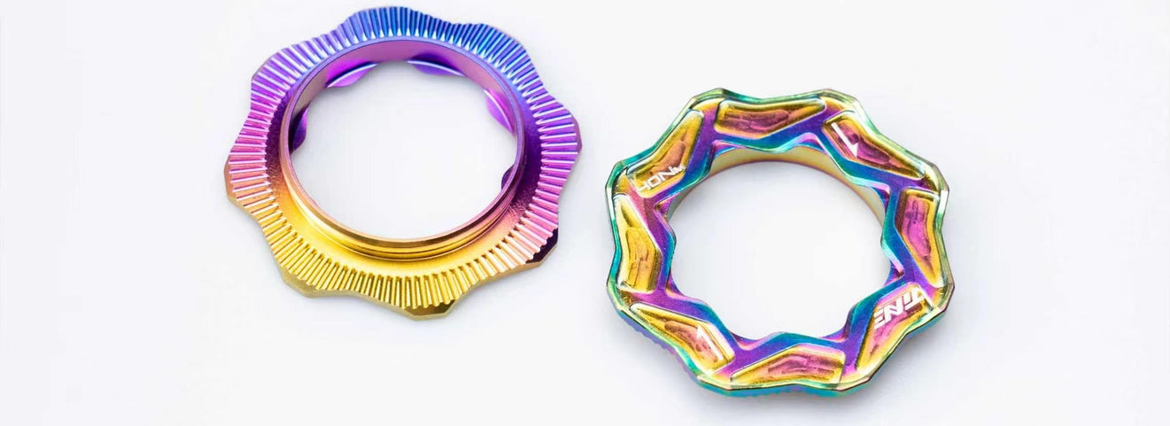 Two TiNE titanium centerlock caps in rainbow anodized finishes