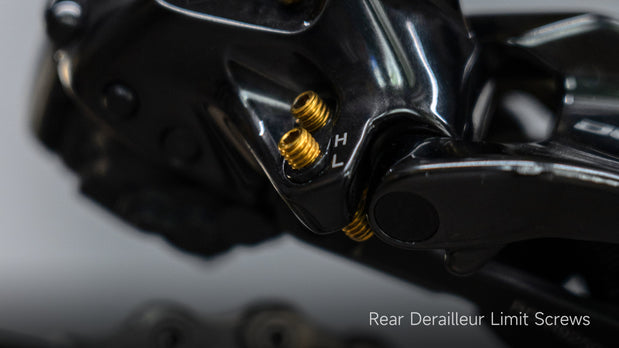 Gold titanium Shimano rear derailleur limit screws installed on black 105 R7170 derailleur, showing L H markings, 1.0 g each vs 3.0 g stock.