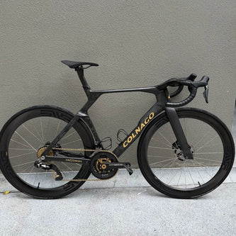 Colnago race bike with titanium upgrades, sleek black frame, gold components