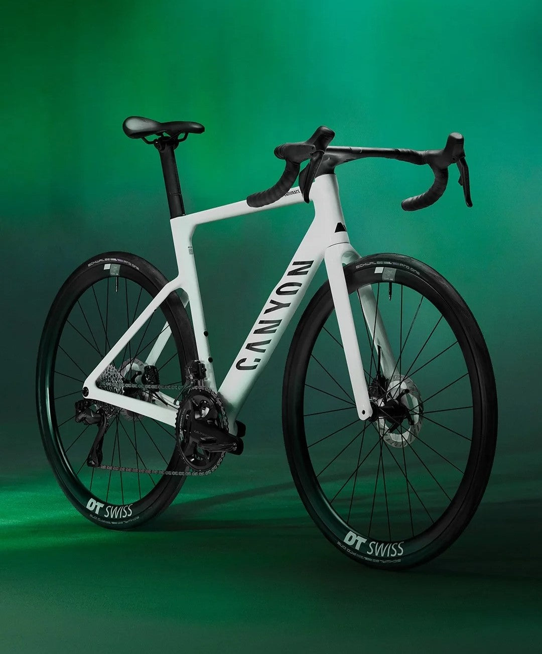 White Canyon road bike with black accents, DT Swiss wheels, green backdrop