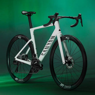 White Canyon road bike with black accents, DT Swiss wheels, green backdrop
